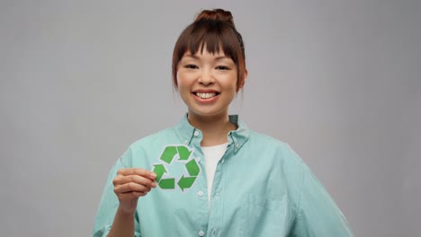 Asiatische-Frau-Mit-Recycling-Schild,-Das-Den-Daumen-Nach-Oben-Zeigt.-Ökologisches-Leben,-Umwelt--Und-Nachhaltigkeitskonzept.-Porträt-Einer-Glücklich-Lächelnden-Jungen-Asiatischen-Frau-In-Türkisfarbenem-Hemd,-Die-Ein-Grünes-Recycling-Schild-Hält-Und-Den-Daumen-Nach-Oben-Auf-Grauem-Hintergrund-Zeigt