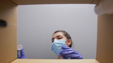 Mujer-Con-Mascarilla-Médica-Protectora-Y-Guantes-Desempacando-Una-Caja-De-Paquete-Con-Cosméticos.-Entrega-A-Domicilio,-Envío-Y-Concepto-De-Pandemia.-Mujer-Con-Mascarilla-Médica-Protectora-Y-Guantes-Desempacando-Una-Caja-De-Paquete-Con-Cosméticos-Y-Productos-De-Belleza.