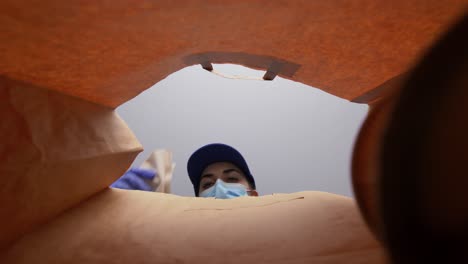 Mujer-Con-Guantes-Y-Mascarilla-Empacando-Comida-En-Bolsa-De-Papel.-Protección-De-La-Salud,-Concepto-De-Entrega-Y-Pandemia.-Mujer-Con-Guantes-Médicos-Protectores-Y-Mascarilla-Empacando-Comida-China-Para-Llevar-En-Una-Bolsa-De-Papel.