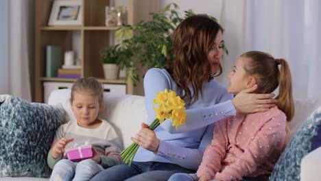 Hijas-Dando-Flores-Y-Regalos-A-La-Feliz-Madre.-Concepto-De-Personas,-Familia-Y-Vacaciones.-Dos-Hijas-Dando-Flores-Y-Regalos-A-La-Feliz-Madre-En-Casa.