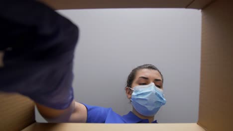 Mujer-Con-Mascarilla-Médica-Protectora-Y-Guantes-Empacando-Una-Caja-De-Paquete-Con-Cosméticos.-Entrega,-Envío-Y-Concepto-De-Pandemia.-Mujer-Con-Mascarilla-Médica-Protectora-Y-Guantes-Empacando-Una-Caja-De-Paquete-Con-Cosméticos-Y-Productos-De-Belleza.