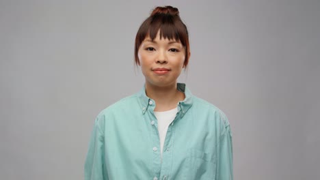 Asian-Woman-with-Recycling-Sign-Showing-Thumbs-Up.eco-living,-environment-and-sustainability-concept-portrait-of-happy-smiling-young-asian-woman-in-turquoise-shirt-holding-green-recycling-sign-and-showing-thumbs-up-over-grey-background