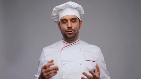 cooking,-culinary-and-blogging-concept--happy-smiling-male-chef-in-toque-and-jacket-videoblogging-and-talking-on-camera-over-grey-background