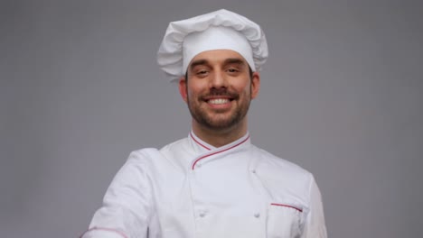 cooking,-culinary-and-people-concept--happy-smiling-male-chef-in-toque-showing-thumbs-up-over-grey-background