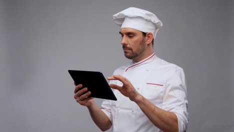 cooking,-culinary-and-technology-concept--male-chef-in-toque-with-tablet-pc-computer-over-grey-background