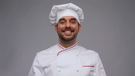 cooking,-culinary-and-people-concept--happy-smiling-male-chef-adjusting-toque-over-grey-background