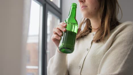 alcoholism,-alcohol-addiction-and-people-concept--drunk-woman-or-female-alcoholic-drinking-beer-from-bottle-at-home