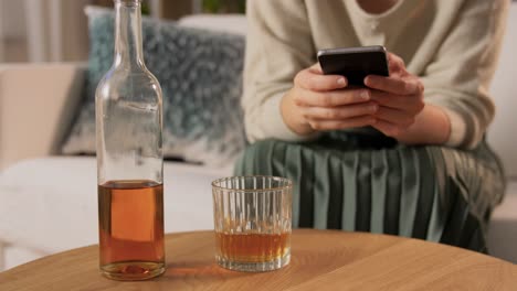 Alkoholismus,-Alkoholsucht-Und-Menschen-Konzept-Betrunkene-Frau-Oder-Weibliche-Alkoholikerin-Mit-Smartphone-Trinken-Whisky-Zu-Hause