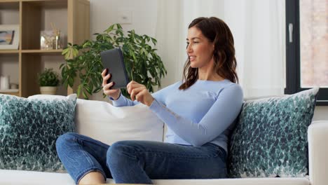 Concepto-De-Gente,-Tecnología-Y-Ocio.-Feliz-Joven-Afroamericana-Sentada-En-Un-Sofá-Con-Una-Computadora-Tablet-Haciendo-Una-Videollamada-Y-Saludando-Con-La-Mano-En-Casa