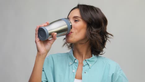 Mujer-Con-Taza-Térmica-O-Vaso-Para-Bebidas-Calientes.-Retrato-De-Concepto-De-Personas-De-Una-Joven-Sonriente-Feliz-Con-Una-Camisa-Turquesa-Con-Taza-Térmica-O-Vaso-Para-Bebidas-Calientes-Sobre-Fondo-Gris