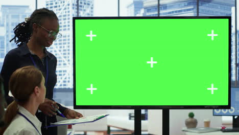 Diverse-work-team-discusses-corporate-strategies-with-a-big-green-screen