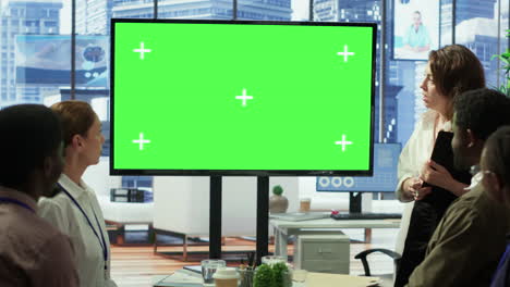 Diverse-group-of-startup-employees-looking-at-green-screen-on-interactive-board