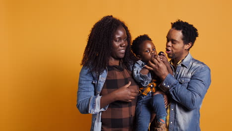 African-american-mom-and-dad-teaching-their-son-how-to-sing-in-studio