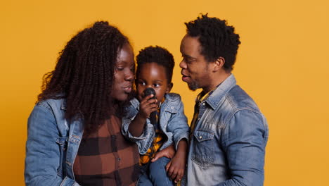 African-american-parents-teaching-their-sweet-toddler-to-sing-on-microphone