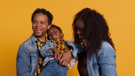 African-american-family-smiling-against-yellow-background-in-studio