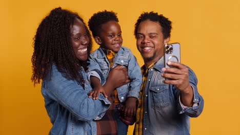 African-american-family-of-three-smiling-for-photos-on-mobile-phone