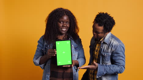 African-american-couple-pointing-at-a-tablet-with-isolated-green-screen-display