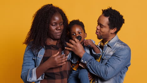 African-american-mom-and-dad-teaching-their-son-how-to-sing-in-studio