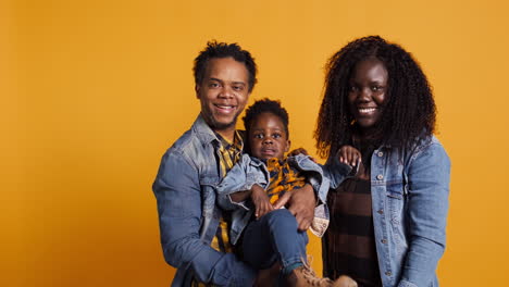 African-american-family-smiling-against-yellow-background-in-studio