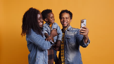 African-american-parents-and-infant-smiling-for-photos-on-phone