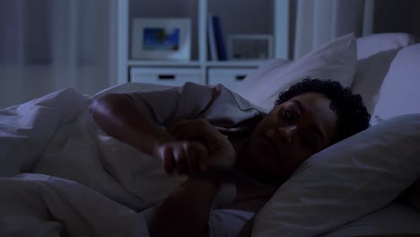 Woman-with-Smartphone-in-Bed-at-Home-at-Night.technology,-internet,-communication-and-people-concept-young-african-american-woman-with-smartphone-lying-in-bed-at-home-at-night