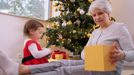 Großmutter-Und-Baby-Mit-Weihnachtsgeschenk-Und-Dekor.-Weihnachten,-Feiertage-Und-Familienkonzept.-Glückliche-Großmutter-Und-Kleine-Enkelin-Mit-Geschenkbox-Und-Dekoration-Zu-Hause