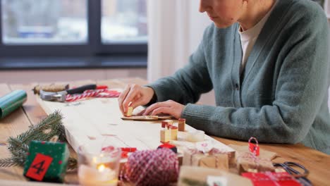 Frau,-Die-Zu-Hause-Einen-Adventskalender-Für-Weihnachten-Bastelt.Winterferien-Und-Hobby-Konzept.-Kreative-Frau-Mit-Briefmarken,-Die-Zu-Hause-Einen-Adventskalender-Für-Weihnachten-Bastelt