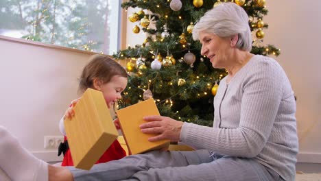 Großmutter-Und-Kleines-Mädchen-öffnen-Weihnachtsgeschenk.Weihnachten,-Feiertage-Und-Familienkonzept.-Glückliche-Großmutter-Und-Kleine-Enkelin-öffnen-Geschenkbox-Zu-Hause