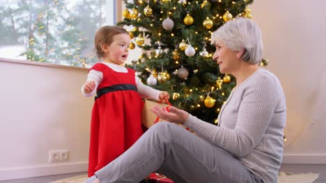 Großmutter-Und-Kleines-Mädchen-öffnen-Weihnachtsgeschenk.Weihnachten,-Feiertage-Und-Familienkonzept.-Glückliche-Großmutter-Und-Kleine-Enkelin-öffnen-Geschenkbox-Zu-Hause