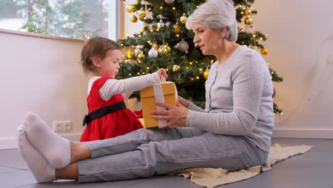 Großmutter-Und-Kleines-Mädchen-öffnen-Weihnachtsgeschenk.Weihnachten,-Feiertage-Und-Familienkonzept.-Glückliche-Großmutter-Und-Kleine-Enkelin-öffnen-Geschenkbox-Zu-Hause