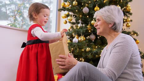 Abuela-Y-Nieta-Abriendo-Regalo-De-Navidad.-Navidad,-Vacaciones-Y-Concepto-Familiar.-Abuela-Feliz-Y-Nieta-Abriendo-Caja-De-Regalo-En-Casa.