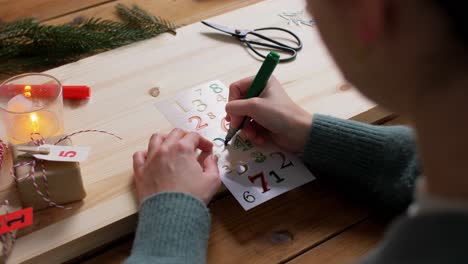 Hands-with-Template-and-Marker-Drawing-Number.winter-holidays-and-hobby-concept-close-up-of-hands-with-template-drawing-number-four-with-green-marker-on-tag-and-making-advent-calender-on-christmas