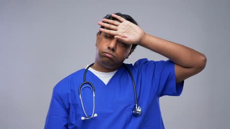 Indian-Male-Doctor-in-Blue-Uniform-Taking-Mask-Off.healthcare,-profession-and-medicine-concept-happy-smiling-indian-doctor-or-male-nurse-in-blue-uniform-taking-off-face-protective-medical-mask-for-protection-from-virus-disease-over-grey-background