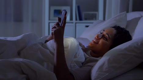 Frau-Mit-Smartphone-Im-Bett-Zu-Hause-In-Der-Nacht.Technologie,-Internet,-Kommunikation-Und-Menschen-Konzept-Junge-Afroamerikanische-Frau-Mit-Smartphone-Im-Bett-Zu-Hause-In-Der-Nacht-Liegen