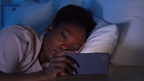 Mujer-Dormida-Que-Se-Despierta-Por-El-Teléfono-Por-La-Noche.-Tecnología,-Internet,-Comunicación-Y-Concepto-De-Personas.-Mujer-Afroamericana-Joven-Durmiendo-En-La-Cama-Y-Despertándose-Por-El-Teléfono-Inteligente-En-Casa-Por-La-Noche.