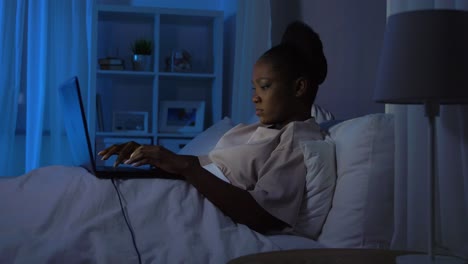 Mujer-Africana-Usando-Una-Computadora-Portátil-En-La-Cama-En-Su-Casa-Por-La-Noche.-Tecnología,-Internet,-Comunicación-Y-Concepto-De-Personas.-Mujer-Afroamericana-Joven-Cansada-Abriendo-Una-Computadora-Portátil-En-La-Cama-En-Su-Casa-Por-La-Noche.