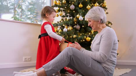 Großmutter-Und-Kleines-Mädchen-öffnen-Weihnachtsgeschenk.Weihnachten,-Feiertage-Und-Familienkonzept.-Glückliche-Großmutter-Und-Kleine-Enkelin-öffnen-Geschenkbox-Zu-Hause