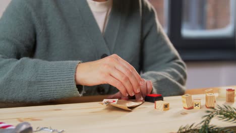 Woman-Making-Advent-Calender-on-Christmas-at-Home.winter-holidays-and-hobby-concept-creative-woman-with-stamps-making-advent-calender-on-christmas-at-home