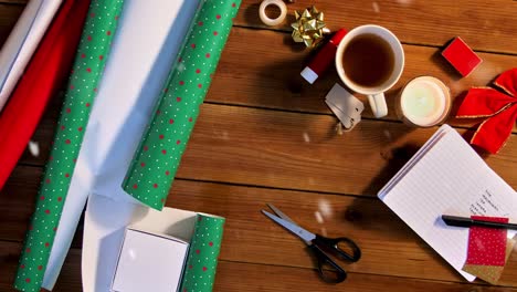 Stuff-for-Christmas-Gifts-Wrapping.holidays,-new-year-and-christmas-concept-–-snow-falling-over-stuff-for-gifts-wrapping-on-wooden-table