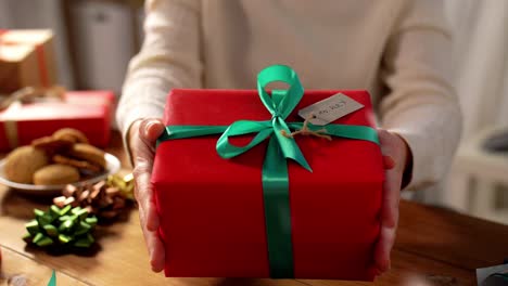 A-Woman-Decorates-a-Christmas-Gift-Box-While-Sitting-on-the-Couch-Women's-Hands-are-Packing-a-New.Women’s-hands-are-packing-a-New-Year’s-gift.-A-woman-decorates-a-Christmas-gift-box-while-sitting-on-the-couch.