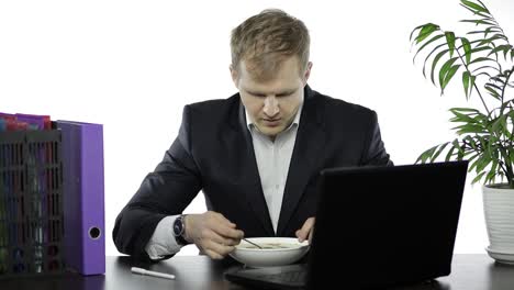 Disheveled-businessman-working-in-office-having-a-lunch-at-the-office-desk