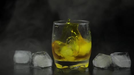 Whiskey-with-ice.-Adding-ice-cubes-on-black-background.-Glass-of-rum-alcohol