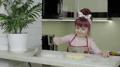 Cooking-pizza.-Little-child-in-apron-sprinkle-the-dough-with-flour-in-kitchen