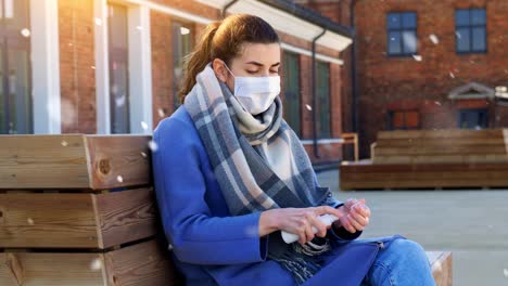 Woman-in-Mask-Using-Hand-Sanitizer-in-Winter-City.hygiene,-health-care-and-safety-concept-–-close-up-of-woman-in-protective-face-mask-spraying-antibacterial-hand-sanitizer-on-city-street-in-winter