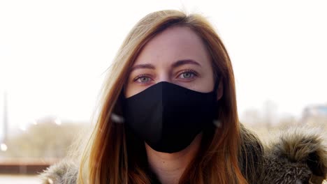 Woman-Wearing-Reusable-Protective-Mask-in-Winter.health,-safety-and-pandemic-concept-–-young-woman-wearing-black-face-protective-reusable-barrier-mask-outdoors-over-snow-in-winter