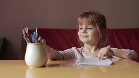 Cute-child-girl-artist-studying-drawing-picture-with-pen-and-pencils-at-home