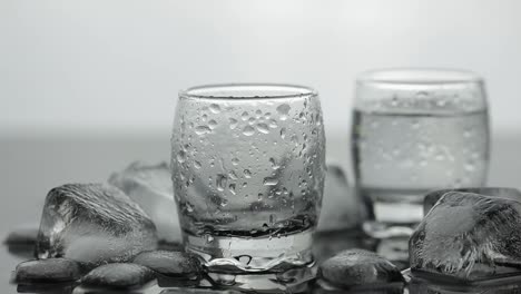 Pouring-up-shot-of-vodka-from-a-bottle-into-glass.-White-background