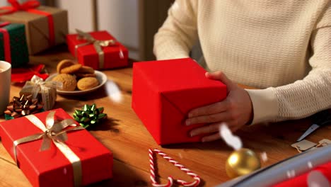 Hände-Packen-Weihnachtsgeschenke-Und-Wählen-Schleife-Aus.-Feiertage,-Neujahr-Und-Weihnachtskonzept-–-Hände-Packen-Geschenkboxen-Und-Wählen-Schleife-Zu-Hause-über-Schnee-Aus