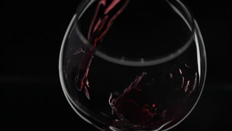 Rose-wine.-Red-wine-pour-in-wine-glass-over-black-background.-Slow-motion