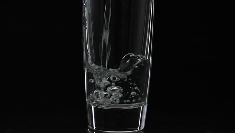 Pouring-up-shot-of-vodka-into-drinking-glass.-Slow-motion.-Black-background